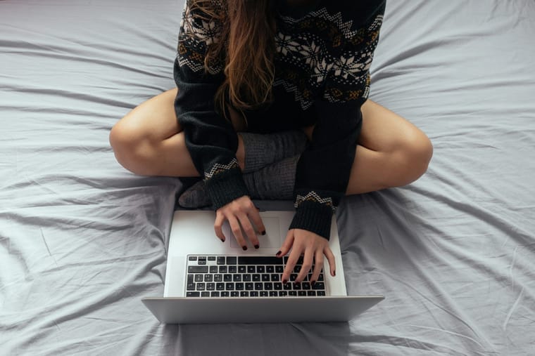 female-typing-laptop-while-sitting-bed-with-crossed-legs-2048x1365.jpg