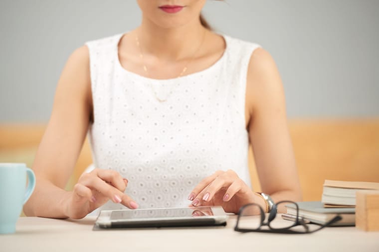 unrecognizable-elegant-woman-sitting-table-using-tablet-2048x1367.jpg